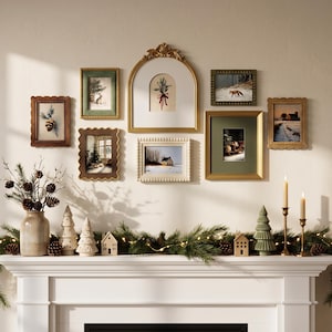 Pode incluir: Uma parede de galeria com oito molduras variadas em tons de dourado, castanho, verde e creme, exibindo arte de inverno. Abaixo, uma lareira branca sustenta um vaso de cerâmica com ramos de pinheiro, pinhas e pequenas figuras de casas.