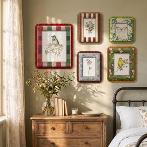 May include: Five rectangular wall frames with fabric borders and fringe, displaying botanical and bird illustrations. The frames feature varied patterns including red and green stripes, brown stripes, green floral prints, and blue floral motifs.