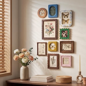 Könnte beinhalten: Eine Galerie-Wandgestaltung mit zehn verschiedenen Bilderrahmen in unterschiedlichen Formen, Farben und Texturen, darunter Holz-, Blau-, Rosa- und Brauntöne. Die Rahmen enthalten botanische Drucke, Schmetterlingsbilder und Karten.