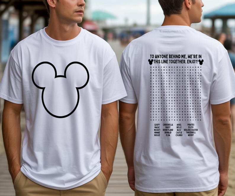 May include: White t-shirt featuring a large black outline of Mickey Mouse's head on the front. The back of the shirt has a word search puzzle with Disney-related words and the text: "TO ANYONE BEHIND ME, WE'RE IN THIS LINE TOGETHER. ENJOY!"