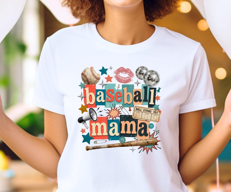 May include: White t-shirt featuring a collage design with the words "baseball mama." The design includes a baseball, lips, disco balls, stars, a megaphone, a baseball bat, and a ticket that says "ball strike out."