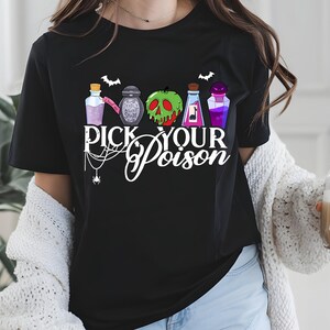 May include: Black t-shirt featuring a graphic with colorful potion bottles, bats, and a spiderweb. The text "PICK YOUR POISON" is displayed in white script. A Halloween-themed design.