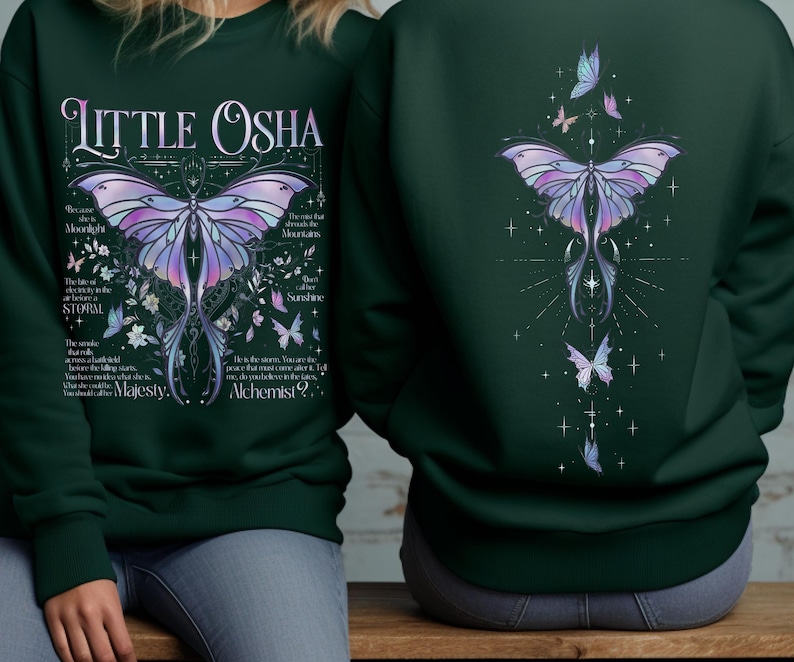 Peut inclure: Sweat-shirt vert fonc&eacute; avec un motif de papillon d&eacute;taill&eacute; en violet, bleu et rose. Le devant affiche le texte "Little Osha" et d'autres textes. Le dos pr&eacute;sente un motif de papillon similaire.