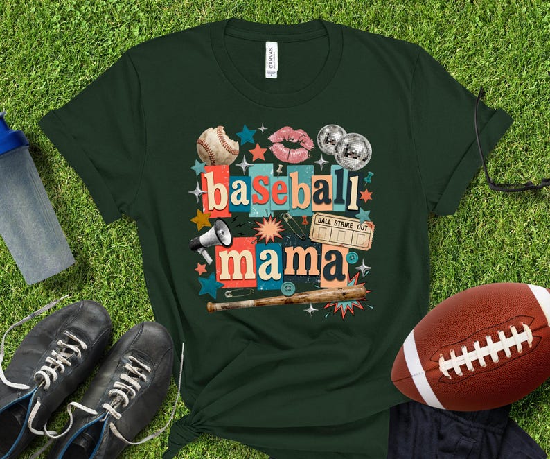 May include: Dark green t-shirt with a baseball-themed graphic. The design includes a baseball, lips, disco balls, and the words "baseball mama." A football, shoes, and a water bottle are also visible.
