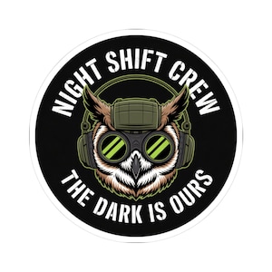 May include: A round sticker featuring an owl wearing goggles and headphones. The owl is brown, white, and green, with the text "NIGHT SHIFT CREW" and "THE DARK IS OURS" in white lettering around the owl.
