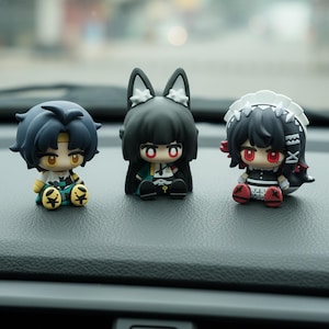 Könnte beinhalten: Drei Anime-Figuren mit großen Augen und detaillierten Outfits. Die Figuren haben dunkle Haare und sitzen. Eine hat blaue Haare, eine andere hat schwarze Haare mit Hasenohren und die dritte hat schwarze Haare und einen weißen Kopfschmuck. Sie befinden sich auf einer dunklen Oberfläche.