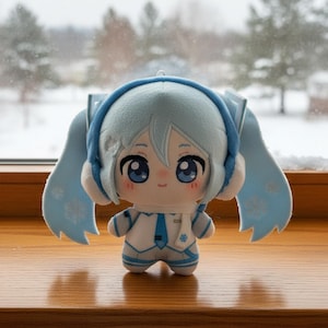 May include: A plush doll featuring light blue hair styled in twin tails with snowflake patterns, wearing a white and blue outfit with a matching tie and scarf. The character has large blue eyes, a small smile, and blue headphones over the ears.