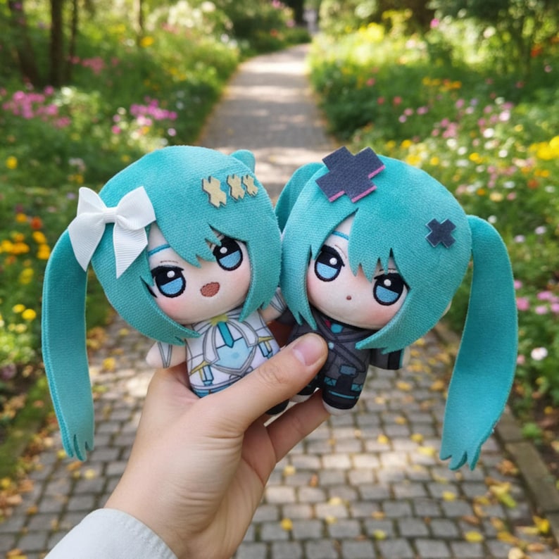 May include: Two plush dolls with teal hair and large eyes are held up in front of a blurred background of greenery. One doll has a white bow and a white and blue outfit. The other doll has a black outfit and a dark pink and black hair accessory.