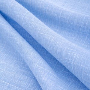 May include: Close-up of a light blue fabric with a subtle grid pattern. The fabric is draped, showing soft folds and textures. The color is a solid, pale blue, suitable for clothing or home decor.