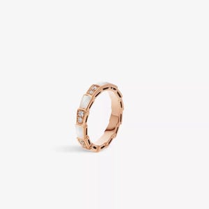 May include: Rose gold ring with a geometric design. The ring features alternating white rectangular inlays and diamond accents. The ring is set against a white background.