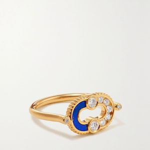 May include: A gold ring with a blue enamel inlay and a cluster of round, clear gemstones. The ring has a unique design with a central oval shape and a delicate band.