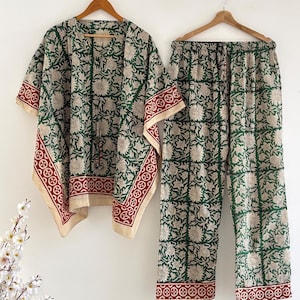 May include: A matching set of green and beige floral print loungewear, including a short-sleeved kimono-style top and pants. The set features a red border with a geometric design. The outfit is hanging on a wooden hanger.