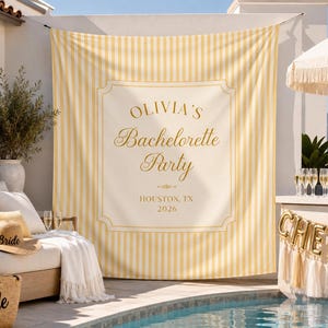 May include: A large rectangular fabric backdrop featuring vertical yellow and white stripes with a central cream-colored panel. The text reads OLIVIA'S Bachelorette Party, HOUSTON, TX, 2026, printed in gold lettering within a decorative border.