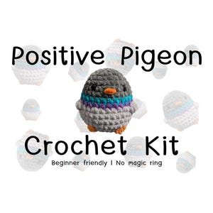 May include: A crochet kit featuring a plush pigeon with a dark grey head, a light grey body, and a neck band of teal and purple yarn. The pigeon has small black eyes and an orange beak. The text reads Positive Pigeon Crochet Kit Beginner friendly I No magic ring.