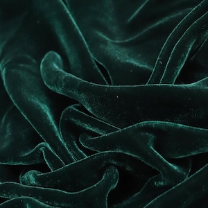 Puede incluir: Una tela de terciopelo verde bosque profundo con un pelo denso y suave con un brillo reflectante. El material est&aacute; drapeado en m&uacute;ltiples pliegues, creando una serie de sombras claras y oscuras en la superficie que resaltan la textura.