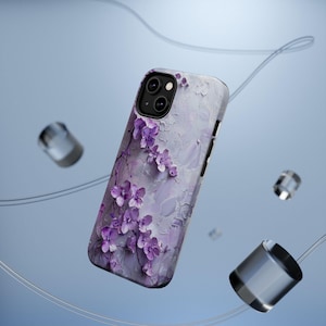 Könnte beinhalten: Eine Handyhülle mit strukturiertem, lavendelfarbenem Hintergrund und floralem Design. Die Hülle zeigt einen Zweig mit lila Orchideen. Die Handyhülle ist ein schützendes Zubehör für ein Smartphone.
