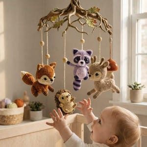 Puede incluir: Móvil para bebé hecho a mano con animales del bosque de ganchillo: un zorro, un mapache, un ciervo, un erizo y una seta. El móvil está suspendido de una rama de madera con hojas y cuentas de madera.