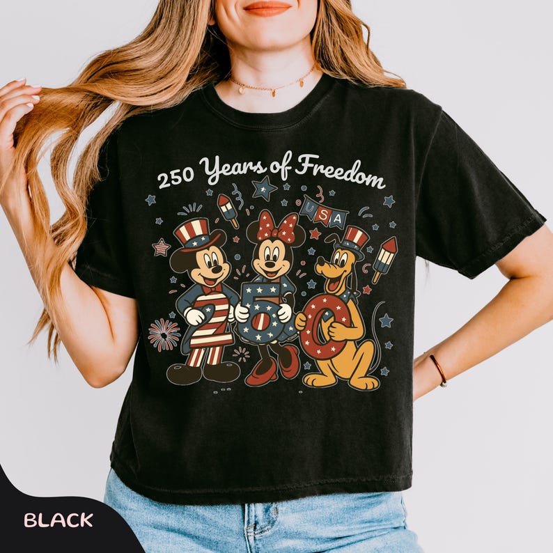 Może przedstawiać: Czarny t-shirt z Myszką Miki, Minnie i Pluto w patriotycznych strojach. Tekst "250 Years of Freedom" z gwiazdami, fajerwerkami i literami "USA".