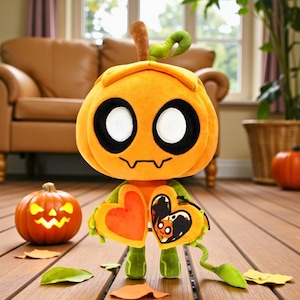 May include: A plush pumpkin character with large white eyes outlined in black, a stitched mouth, and a stem. It holds two heart-shaped objects, one orange and one yellow. The character is on a wooden surface, with a lit jack-o'-lantern in the background.