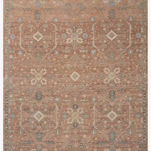 以下が含まれることがあります： テラコッタ色の長方形のラグで、複雑で対称的な模様が特徴です。デザインは、青、ベージュ、クリーム色を基調とした花柄と幾何学模様です。「Carpet Vintage Design」の文字が下部に表示されています。