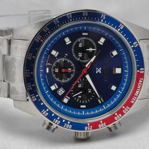 Può includere: Orologio da polso in acciaio inossidabile con quadrante blu e lunetta blu e rossa. L'orologio presenta più quadranti secondari, un datario e una scala tachimetrica. Il cinturino è in acciaio inossidabile.