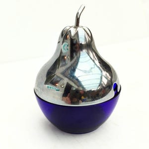 Può includere: Un contenitore decorativo a forma di pera con una parte superiore argentata lucida e una base blu scuro. La parte superiore argentata ha uno stelo e riflette l'ambiente circostante. Il contenitore è probabilmente in vetro e metallo.