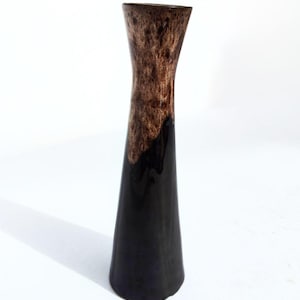 May include: A two-tone vase with a glossy black base and a textured brown upper section. The vase has a flared top and a conical shape. The height is approximately 25 cm, making it suitable for displaying flowers or as a decorative item.