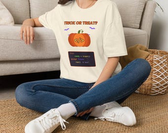 May include: An off-white short-sleeve t-shirt featuring the text TRICK OR TREAT? above an orange pumpkin graphic with code brackets. Below the pumpkin is a dark rectangular box with code text: try: candy = treat() except Trick: run() # boo!