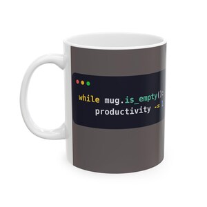 May include: A white ceramic mug featuring a dark gray rectangular graphic that mimics a computer code editor window. The text reads: while mug.is_empty(): productivity -= 1, with syntax highlighting in yellow, green, and blue colors.