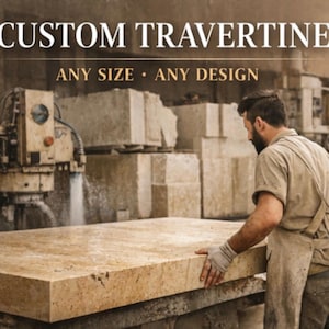 Pode incluir: Um trabalhador numa oficina examina uma grande laje retangular de travertino personalizado. O texto "CUSTOM TRAVERTINE" é exibido acima, com "ANY SIZE • ANY DESIGN" abaixo. A pedra tem uma cor castanha clara e está a ser trabalhada com máquinas.
