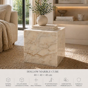 May include: A marble cube side table with a natural veined pattern. The cube measures 15.7 x 15.7 x 15.7 inches and features a hollow interior. The text on the image reads "HOLLOW MARBLE CUBE" and "A DEMOCRACY OF IMAGERY".