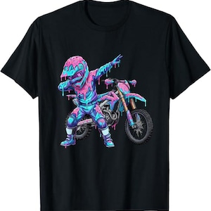 May include: A black short-sleeve t-shirt featuring a graphic of a motocross rider in a dabbing pose next to a dirt bike. The rider and bike are covered in a vibrant pink and blue melting liquid effect, creating a colorful contrast against the black fabric.