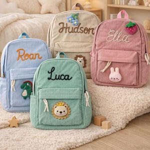 May include: Four corduroy backpacks in pastel colors: light blue, beige, mint green, and pink. Each backpack has a name embroidered on it: Roan, Hudson, Luca, and Ella. The backpacks have decorative patches and are designed for children.