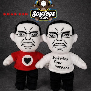 Pode incluir: Duas bonecas de pelúcia com rostos brancos, cabelo preto e óculos. Uma boneca usa uma camisa vermelha com um coração preto, a outra uma camisa branca com "Nothing Ever happens". Calças pretas e um logotipo "SoyToys.com" também são visíveis.