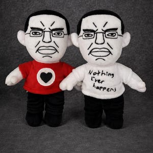 Peut inclure: Deux poupées en peluche avec des expressions sévères et des lunettes. L'une porte un t-shirt rouge avec un cœur noir, l'autre un t-shirt blanc avec "Nothing Ever Happens". Les deux ont des cheveux et des pantalons noirs. Le texte "read bio" est au-dessus.