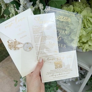 May include: Wedding invitation suite featuring a cream-colored envelope with gold foil text and a wax seal. Includes transparent cards with gold text detailing event information and a QR code for RSVP. The suite is for Sofia & Nasser.