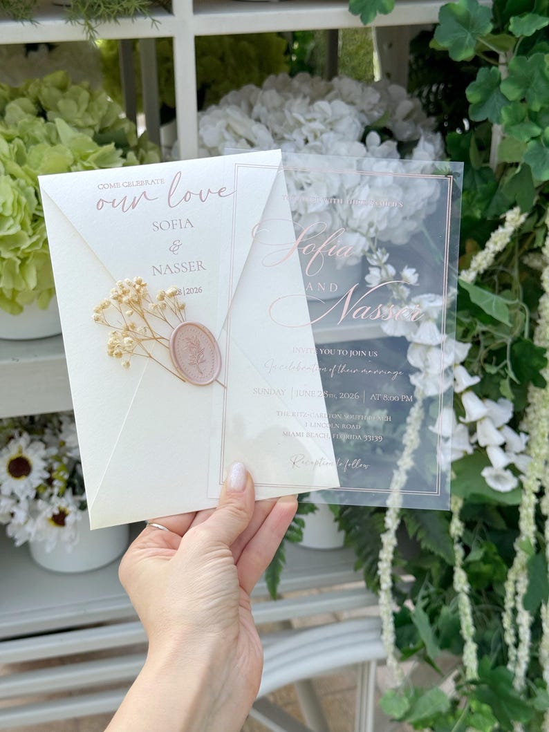 May include: Wedding invitation featuring the names Sofia & Nasser. The invitation is on a cream-colored envelope with a wax seal and dried flowers. A clear overlay displays the names and event details.