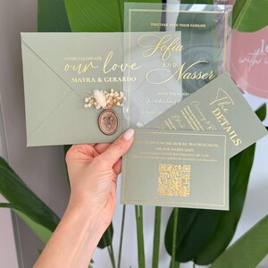 May include: Sage green wedding invitation suite with gold foil lettering. The invitation includes an envelope, a clear acrylic card, and a details card. The envelope is sealed with a wax stamp and dried flowers. The text reads "Come Celebrate our love Mayra & Gerardo".