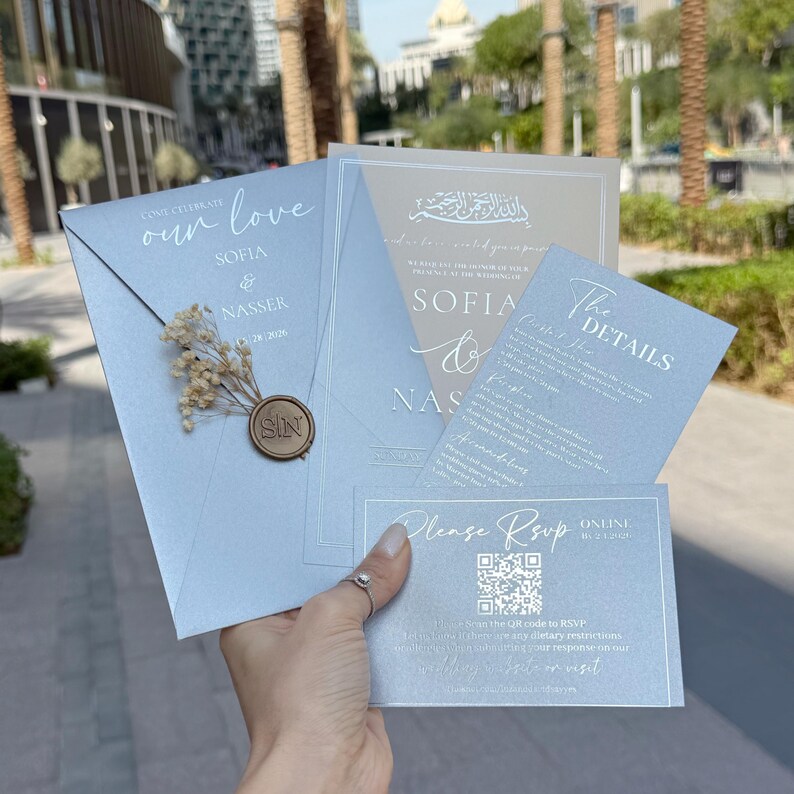 May include: A collection of light blue wedding invitations with elegant calligraphy. The invitations include the names "Sofia & Nasser", a wax seal, and a "Please RSVP" card with a QR code. The overall theme is a formal wedding.
