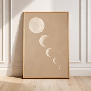 May include: A rectangular wall art print in a light wooden frame featuring a series of five moon phases in varying sizes, depicted in off-white against a solid, muted tan background, arranged in a diagonal line from the top left to bottom right.
