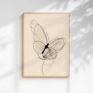 May include: A framed wall art print featuring a black line drawing of a butterfly on a solid light beige background. The butterfly illustration is composed of thin, overlapping lines that create a delicate, layered wing structure and body.