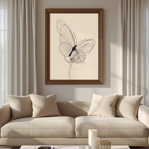 May include: A framed wall art print featuring a black line drawing of a butterfly on a light beige background. The butterfly is depicted with delicate, overlapping lines that create a sense of motion and transparency within a dark brown frame.