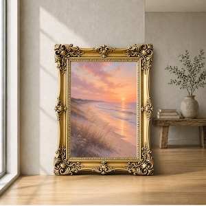 May include: A framed landscape painting of a beach scene at sunset. The painting features a gold frame with ornate detailing. The artwork depicts a beach with waves, sand, and a colourful sky with shades of pink, orange, and yellow.