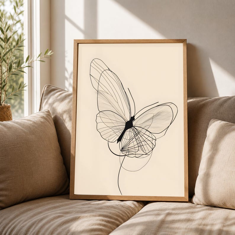 May include: A framed wall art print featuring a black line drawing of a butterfly on a cream-colored background. The butterfly illustration is composed of thin, overlapping lines that create a delicate, layered wing structure within a wooden frame.