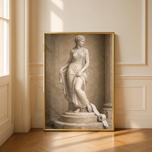 May include: A framed print featuring a classical statue of a woman in a flowing gown. The statue is on a pedestal, with a roll of toilet paper at her feet. The artwork has a sepia tone and is in a gold frame.