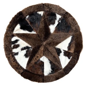 May include: Round cowhide rug with a star design. The rug features a brown star in the center, surrounded by sections of black, white, and brown cowhide. The outer edge is a darker brown, creating a defined border.