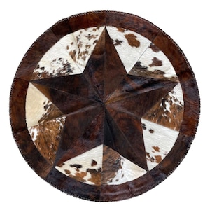 May include: Round cowhide rug featuring a large star design. The star is composed of dark brown and white cowhide patches, with a dark brown border. The rug has a rustic, western aesthetic.