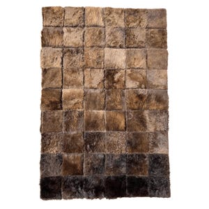 May include: A rectangular rug composed of numerous square patches of varying shades of brown. The patches create a gradient effect, transitioning from lighter browns at the top to darker, almost black, tones at the bottom. The rug has a textured, fur-like appearance.