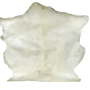 May include: A cream-colored, irregularly shaped piece of leather. The hide has a natural, uneven texture with subtle variations in tone. The edges are rough and unfinished, and the overall appearance suggests a raw, unprocessed material.