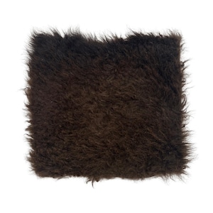 May include: A square, dark brown, shaggy fur textile. The fur is dense and has a slightly uneven texture, with visible strands and a natural, untamed appearance. The edges are slightly frayed, adding to the rustic aesthetic. The overall color is a deep, rich brown.